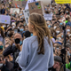 Greta Thunberg onstage in front of a large crowd holding signs at a climate strike in Berlin, Germany.